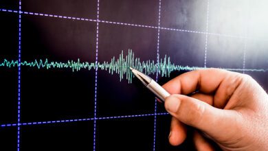 gempa bumi hand with pencil points web earthquake graph on monitor